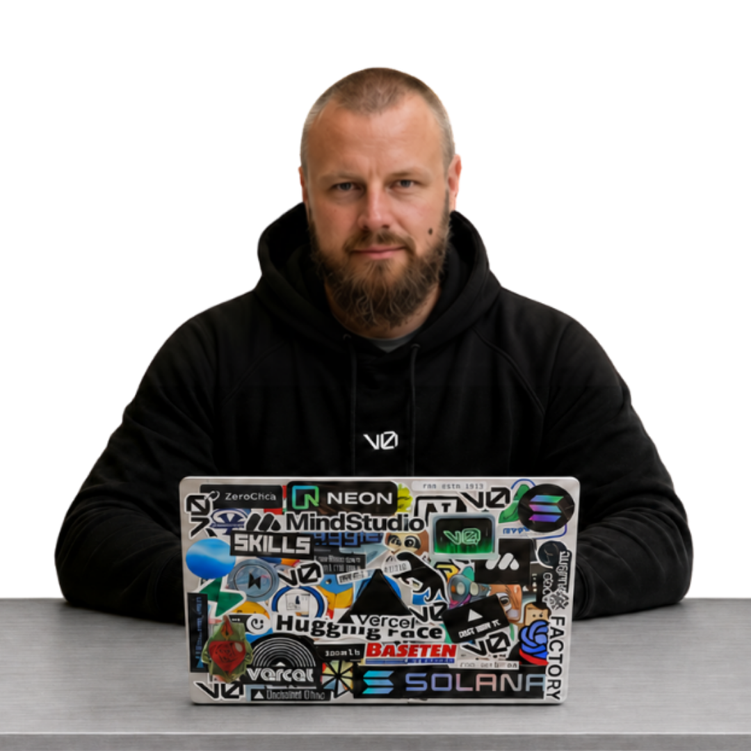 Jon in a v0 hoodie at a desk behind a sticker-covered laptop